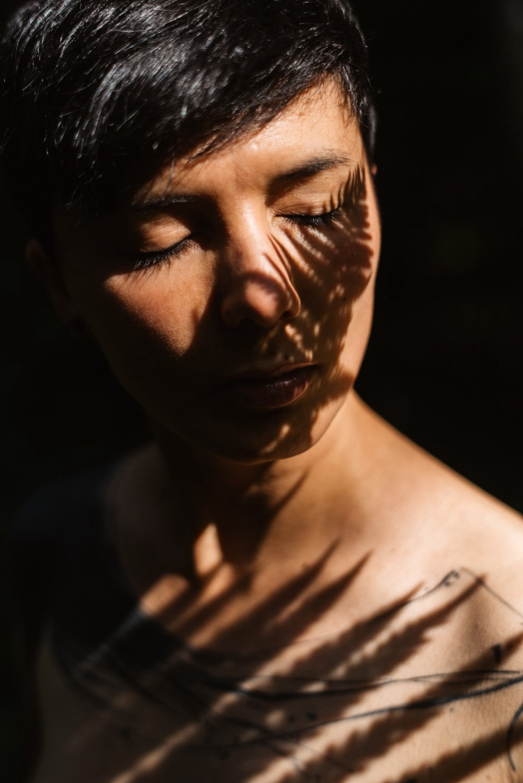 Portrait de Nadège, yeux fermés, ombres de feuillage sur le visage